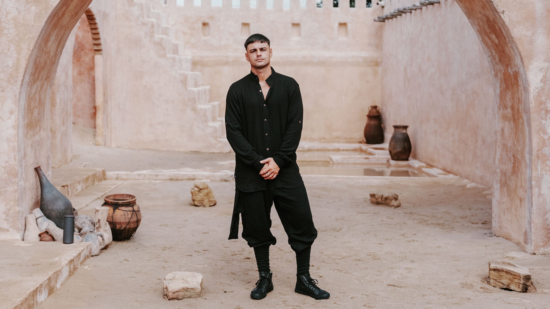 A middle-eastern setting with a man standing and wearing a modern oriental style clothing.