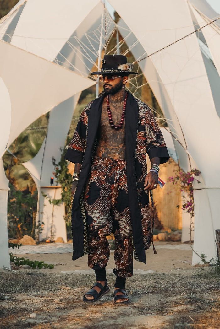 Man walking in a unique bali batik print patterned matching kimono pants outfit, wearing a hat, sunglasses and sandals
 