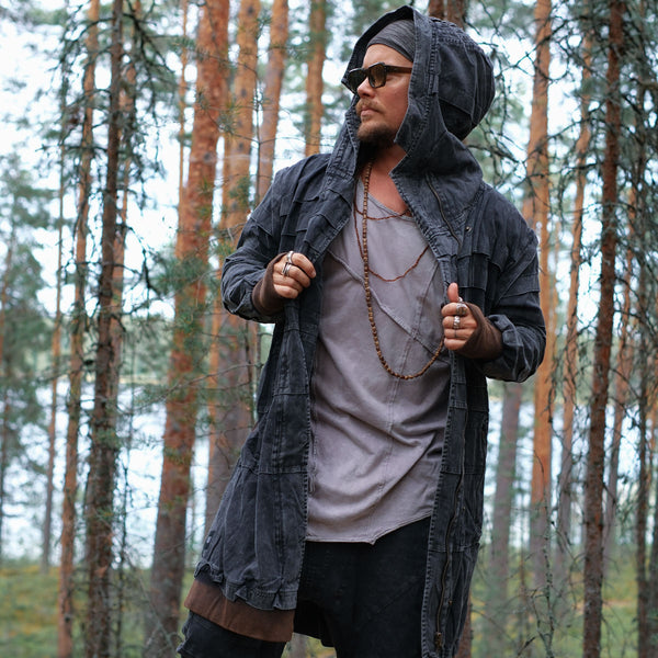 Person wearing a dark hooded jacket in a forest setting